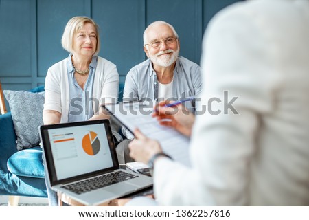 Happy senior couple during the meeting with agent or financial consultant, signing some agreement in the comfortable office Royalty-Free Stock Photo #1362257816