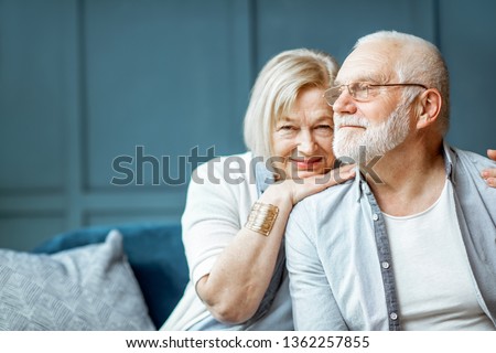Portrait of a beautiful senior couple embracing each other, sitting on the couch at home