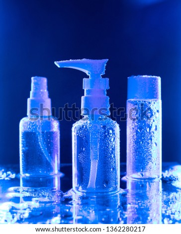 Three spray bottle under a blue light against deep blue backdrop, creative photo of different kinds of flacons with deep blue glow. Conceptual and advertising photo for pharma, cosmetics and beauty