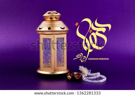 Ramadan Mubarak Written in Arabic.Arabic Lantern Dates on wooden table with purple background.