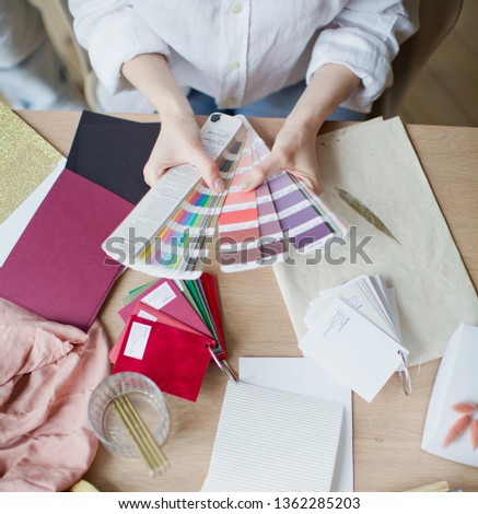Woman at workplace choosing colourful paper charts