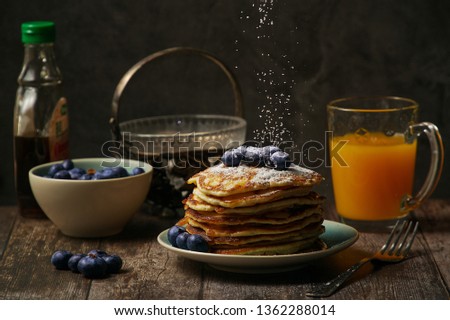 american pancakes with blueberries, maple syrup and powdered sugar, dark background, dark mood  photography