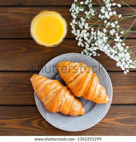 delicious breakfast with croissants, flowers and juice, good morning. Glass of refreshing orange fruit juice. Top view, square image