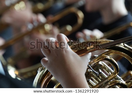 French horn and child hands. Musical brass instruments, adults and children. Concert in the school.  Royalty-Free Stock Photo #1362291920
