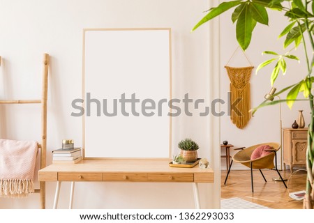 Sunny scanidnavian interiors of apartment with mock up poster frame, wooden ladder, gold armchair, design accessories and furnitures, plants and yellow macrame. Stylish home decor of rooms. Real photo