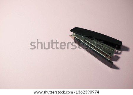 Stapler with clips on a pink background