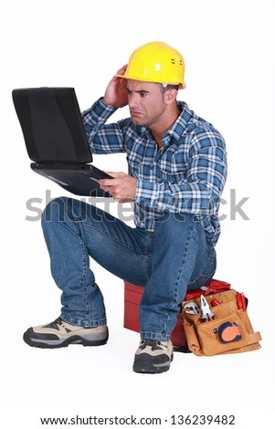 Confused builder sat with laptop