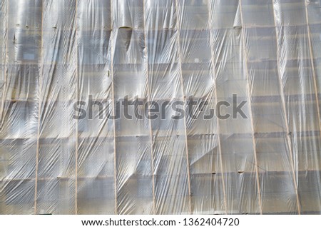 View of the scaffolding covered with protective film during the construction of the school. Technologies. Backgrounds and textures.