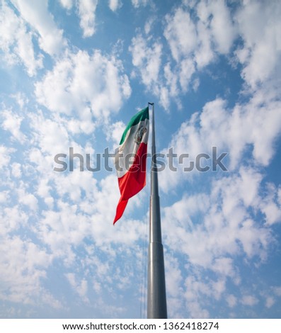 Mexican flag fluttering over a cloud sky.