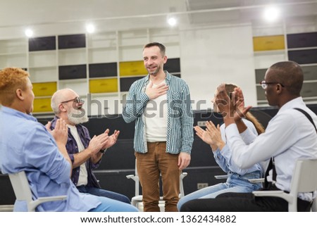Portrait of smiling mature man    introducing himself during therapy session in support group to people clapping, copy space Royalty-Free Stock Photo #1362434882
