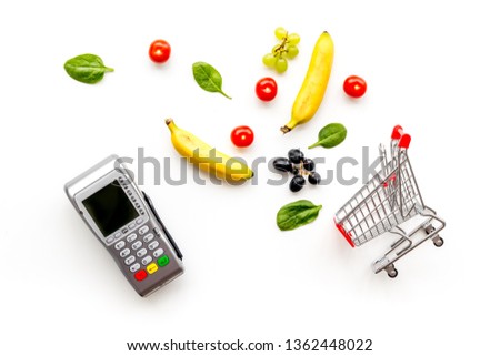 buying products with card machine, fruits and mini trolley on white background top view