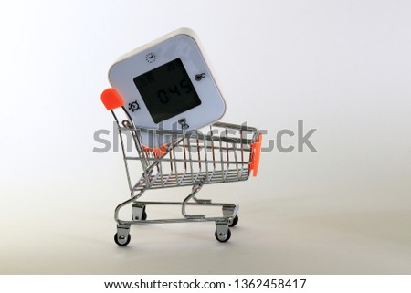 Trolley and table clock over white background. It is shopping time with trolley.