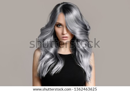 Beautiful woman with long wavy coloring hair. Flat gray background. Royalty-Free Stock Photo #1362463625