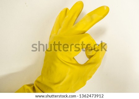 Woman’s hand in yellow rubber glove makes the sign “ok”