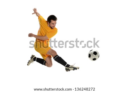 Soccer player wearing a yellow uniform kicking the ball on a white background Royalty-Free Stock Photo #136248272