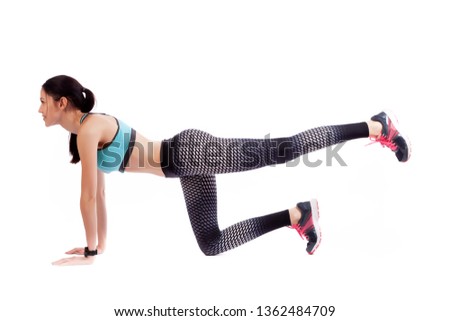 A dark-haired woman coach in a sporty  short top and gym makes and stretch  legs, doing exercise on a  white isolated background in studio. Fit girl living an active lifestyle