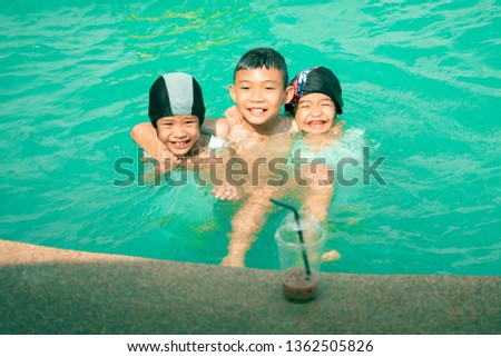 Happy kids swimming and playing in swimming pool on summer holidays 