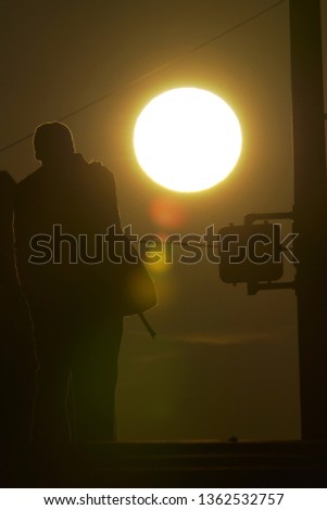 a man walking with silhouetted against the setting sun backgorund - Image