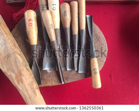 Equipment for hand carving Placed on circular wooden cutting board,On table covered with red cloth.Set of Carving tools made of steel with wooden handle. Carver's tools,occupation that requires talent