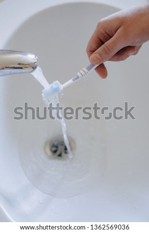 washing the toothbrush under the water flow in the washbasin, morning hygiene