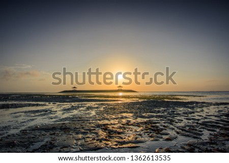 Sunrise over the sea on Bali in Indonesia, ebb with 2 temples in the water. blue picture look