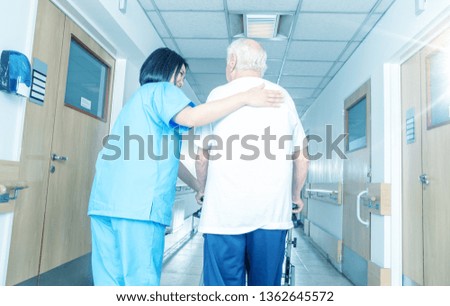 Asian female doctor reassuring mature elderly man with walker. Man and woman smiling happy in the hospital aisle. Retirement community concept.