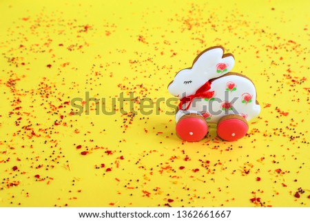 Easter holiday concept, handmade pink and  white gingerbread in the form of a bunny on a yellow background. Gingerbread  rabbit in the spring