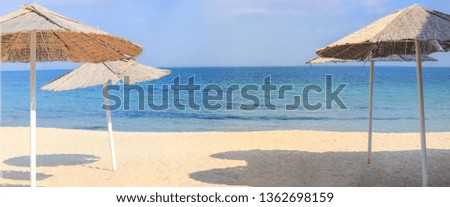Beach umbrellas and clean sand against the backdrop of the azure coast of the sea. Vacation and Tourism concept.