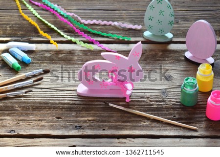 Making Easter decoration - easter eggs and bunny. Painting and coloring wooden toy of brushes and gouache. Creative process. Childrens DIY concept.