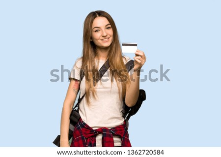 Young photographer woman holding a credit card on isolated blue background