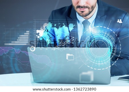 Unrecognizable young businessman looking at laptop with double exposure of global business interface and HUD. Toned image. Elements of this image furnished by NASA