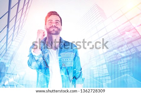 Smiling man in casual clothes celebrating financial victory over modern city background with double exposure of graphs. Startup concept. Toned image