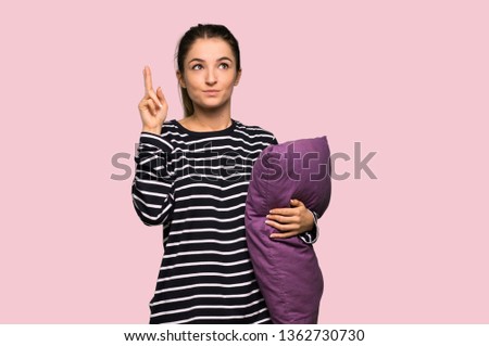 Pretty woman in pajamas with fingers crossing and wishing the best on isolated pink background