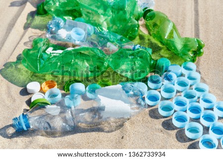 Close up picture of used plastic bottles and caps on a beach, selective focus.