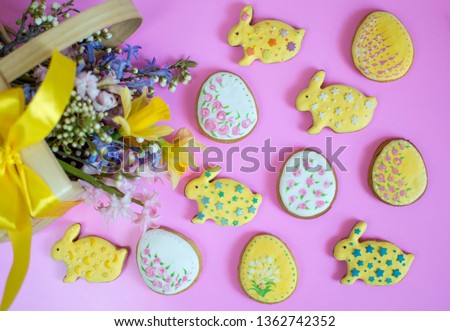 
Easter arrangement of cookies in the shape of Easter rabbits and eggs on a pink background