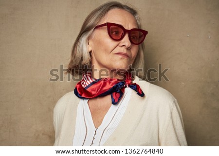 Elderly woman with glasses and a scarf around her neck                