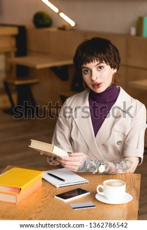 attractive, confident businesswoman sitting in cafeteria and holding book