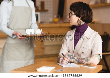 cropped view of waitress with tray standing near trendy businesswoman 