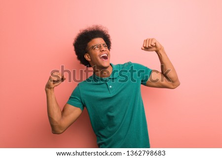 Young african american man over a pink wall who does not surrender