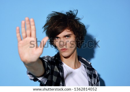 Cute guy with disheveled hair in a plaid shirt blue background