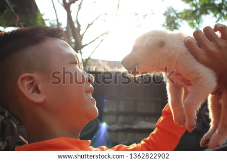 The boy is playing with a puppy with love, the light from the sun in the morning, taking a blurred picture