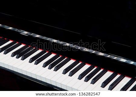 diagonal angle of black upright piano keyboard.  Black background with copy space.
