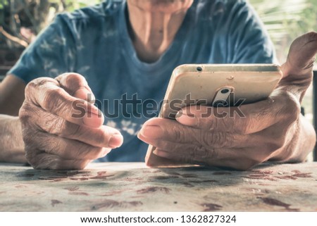 Asian old women hands playing social media in smart phone on the table vintage filter