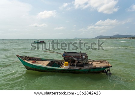 Worn out fishing boat on the sea and in background blue sky with clouds and mountains, picture from Phu Quoq Island, Vietnam.
