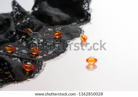 textured black lace with orange beads on white background with copy space