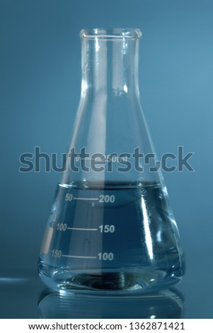 Close up photo of chemical glassware with exam liquids over blue background