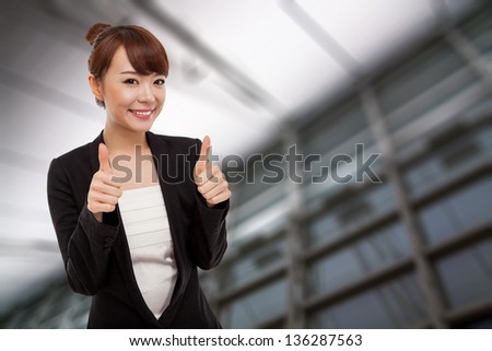Successful happy Asian businesswoman showing thumb isolated on business background.