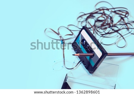 Top view cassette tape over white background with tangled ribbon with pencil to rewind Royalty-Free Stock Photo #1362898601