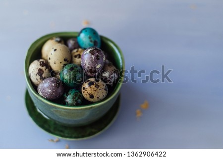 Easter quail eggs in a green ceramic plate on a blue background