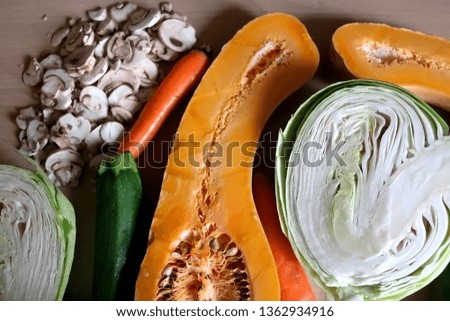 Arrangement of raw food ingredients on the table: butternut squash, cabbage, zucchini, carrot and champignon mushroom. Selective focus.